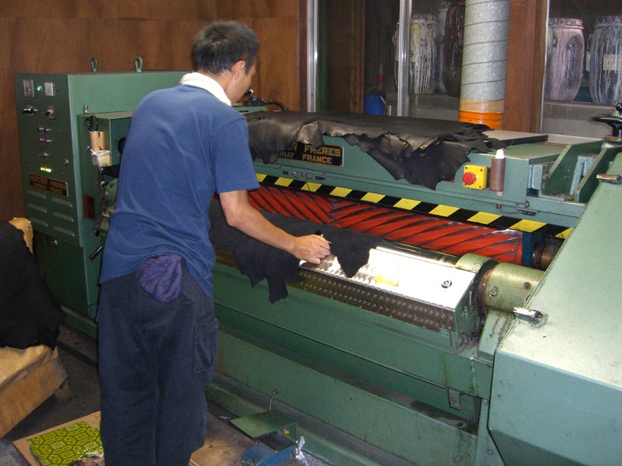 革に熱を加えて、色や薬品を定着させるプレスの作業。